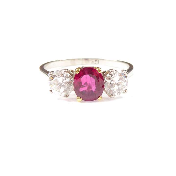 Ruby and diamond three stone ring, claw set with an oval cut Burma ruby,